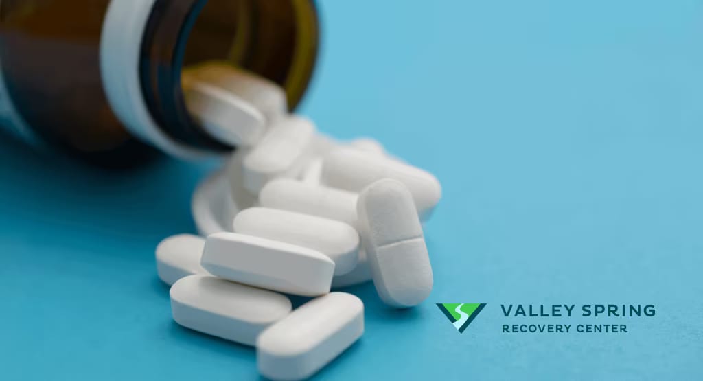 Prescription tablets on a blue surface beside the Valley Spring Recovery Center logo, representing the benzodiazepine class that includes Klonopin