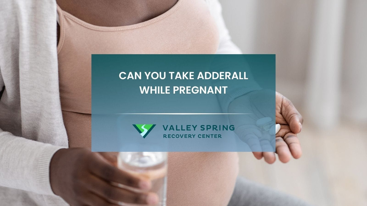 Pregnant patient holding prescribed medication while considering amphetamine-dextroamphetamine safety with an obstetric clinician