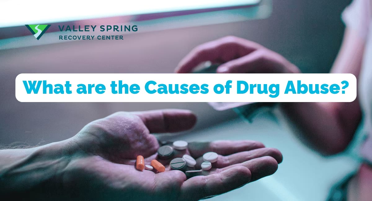 An open hand holding assorted loose pills, illustrating the causes of drug abuse