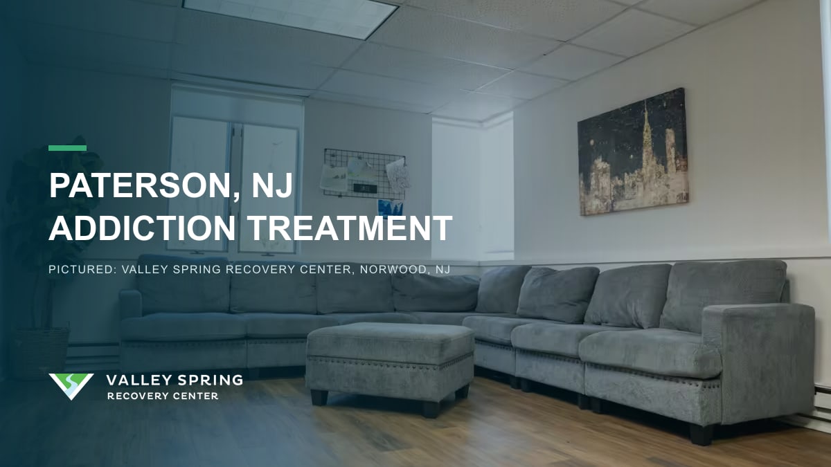Lounge with a gray sectional sofa inside Valley Spring Recovery Center in Norwood, New Jersey, branded for Paterson addiction treatment access