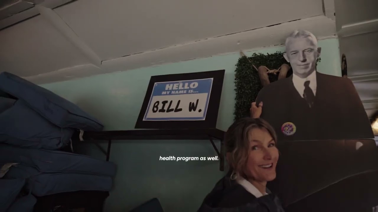 Recovery Day 2026 video still showing an attendee beside a Bill W. display at the community event