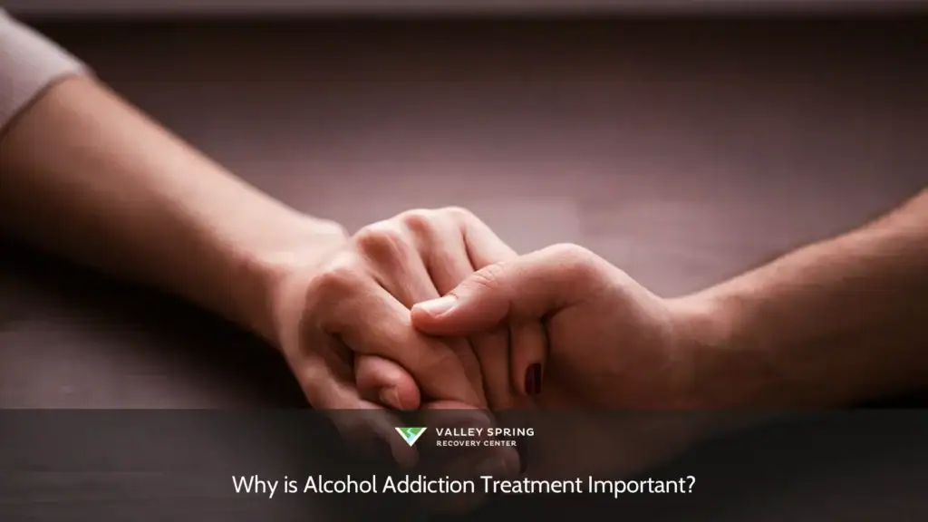 Two hands gently clasped together on a wooden surface, symbolizing support and connection in the context of alcohol addiction treatment.