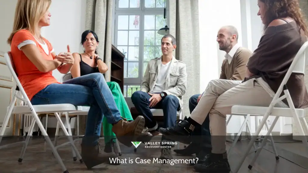 Group discussion in a bright room, with five individuals engaged in conversation about case management strategies and support techniques.
