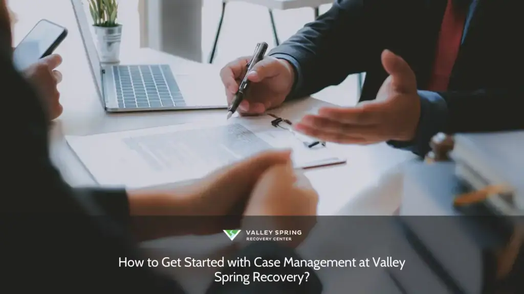 Discussion on case management strategies at Valley Spring Recovery, with individuals reviewing documents at a desk with a laptop and phone.
