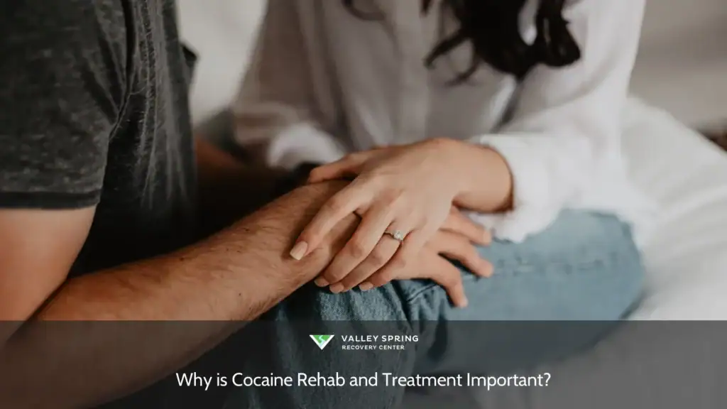 Couple holds hands tenderly, showcasing an engagement ring, symbolizing love and commitment during an intimate moment.